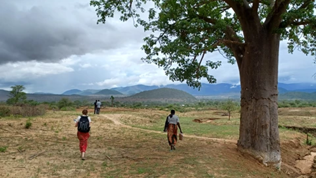 A few persons walking across a field.