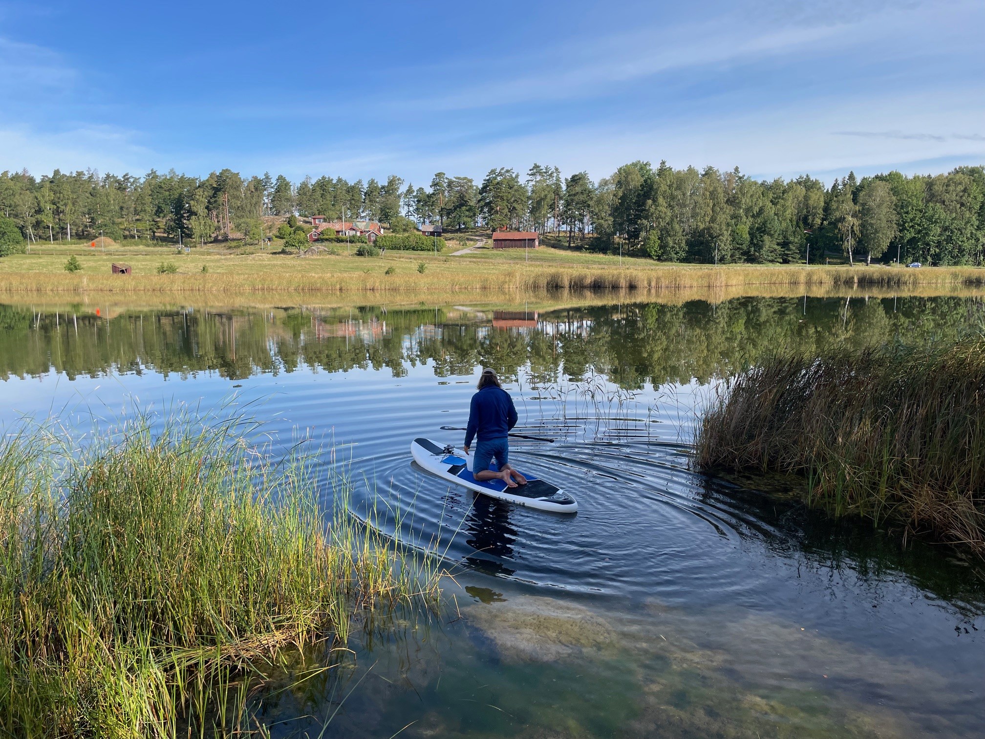 En person står på knä på en stand up paddle board