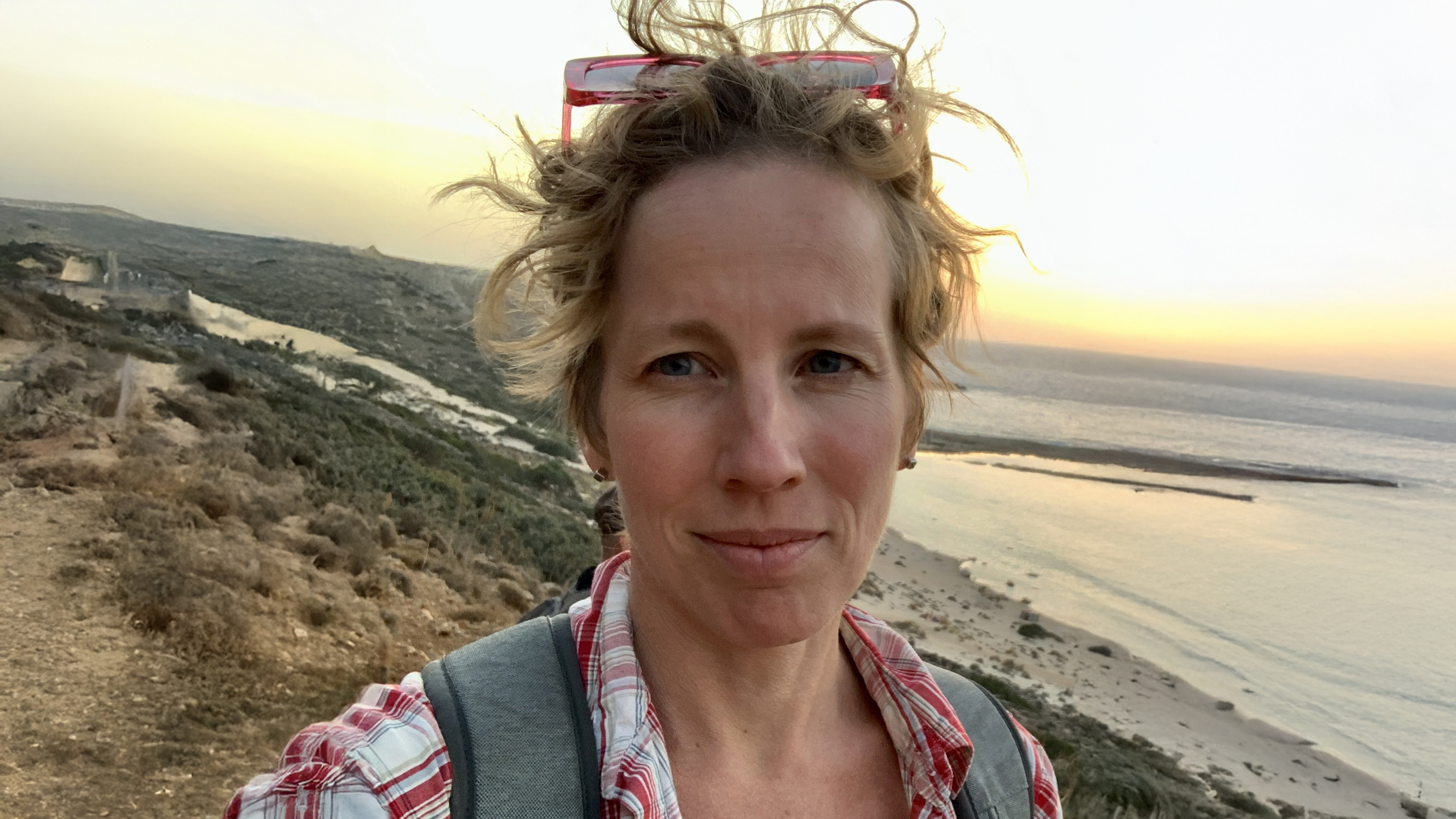 Portrait of a woman, outdoors by the sea at sunset.