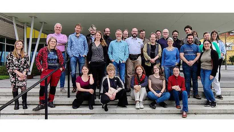 Gruppbild där människor står på trappa utomhus och tittar in i kameran. Foto