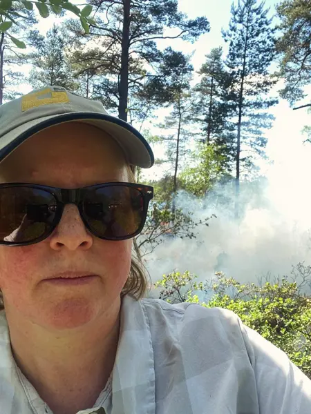 Kvinna i skog omgiven av rök