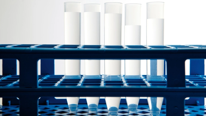Test tubes in a blue container, containing transparent liquids.