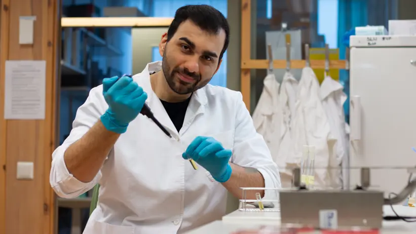 Photo of a man (Homayoon Davam, SLU) wearing a lab coat working in a laboratory.