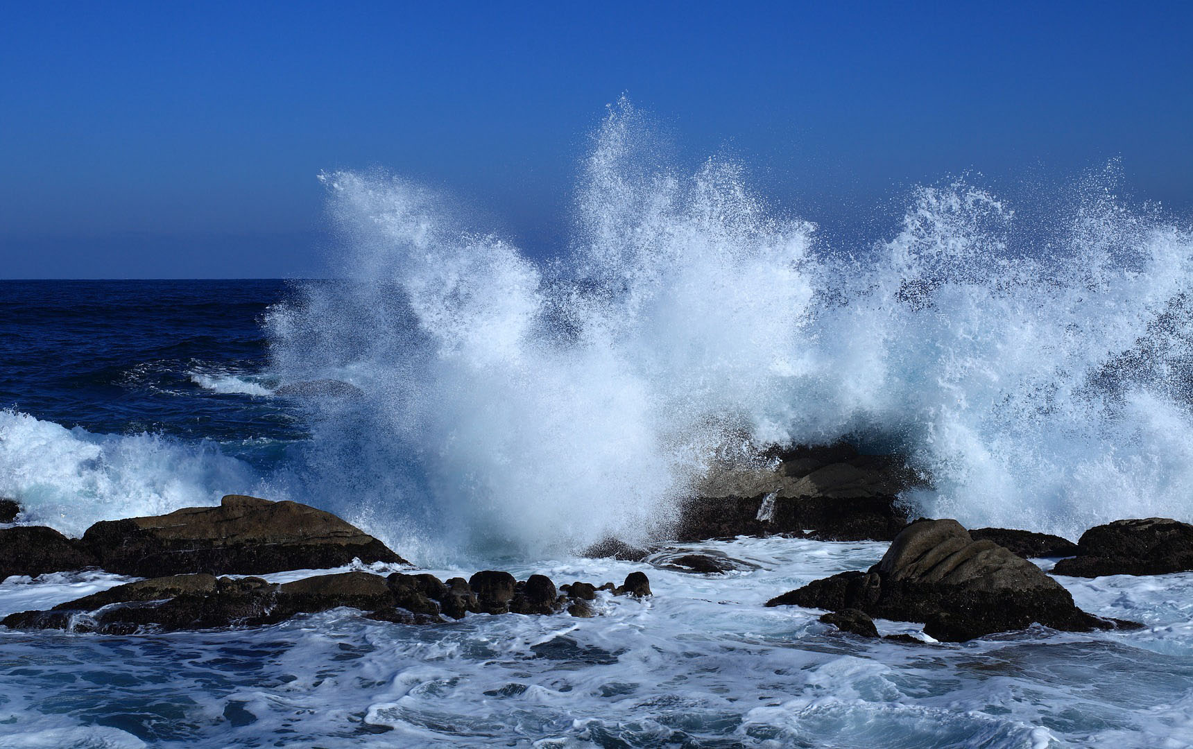 Vågor som slår in över klippor.