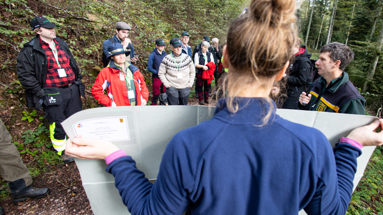 kvinna håller en plansch framför en grupp skogen 