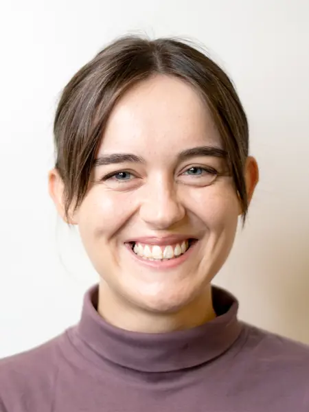 Portrait photo of a smiling woman with brown, updo hair.