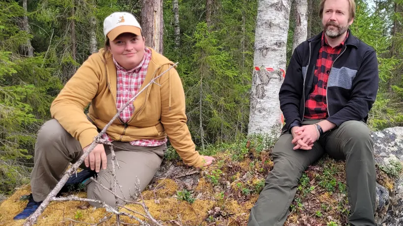 Doktoranderna Sarah och Mathias sitter på en sten i skogen en sommardag.