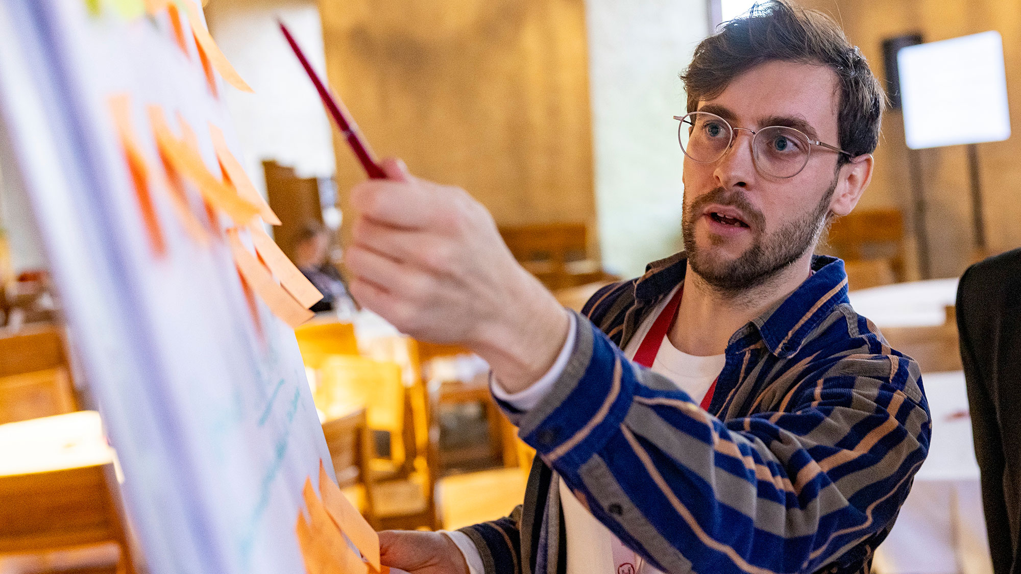 En man står vid ett blädderblock och pekar på post it-lappar. Foto.