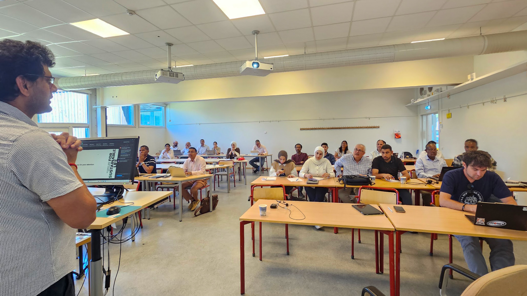 A man lecturing in front of an audience. Photo.