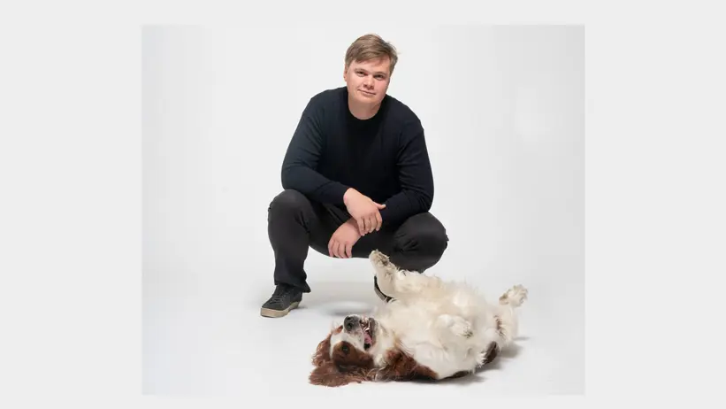 En man sitter på huk bredvid en hund
