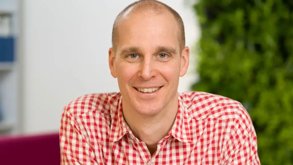 Närbild på en man med rödvitrutig skjorta.