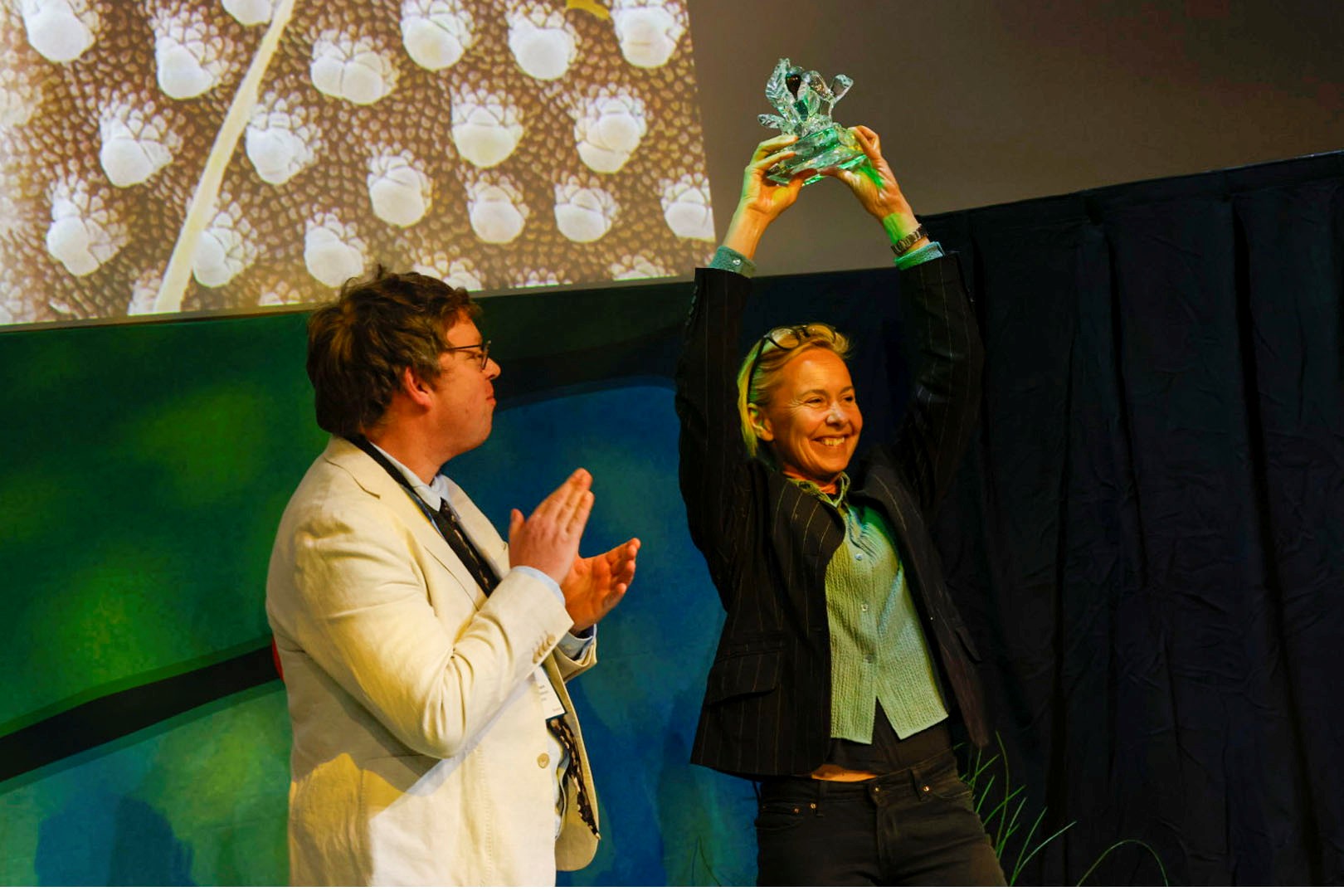 Kvinna med ljust hår håller upp ett pris. Foto