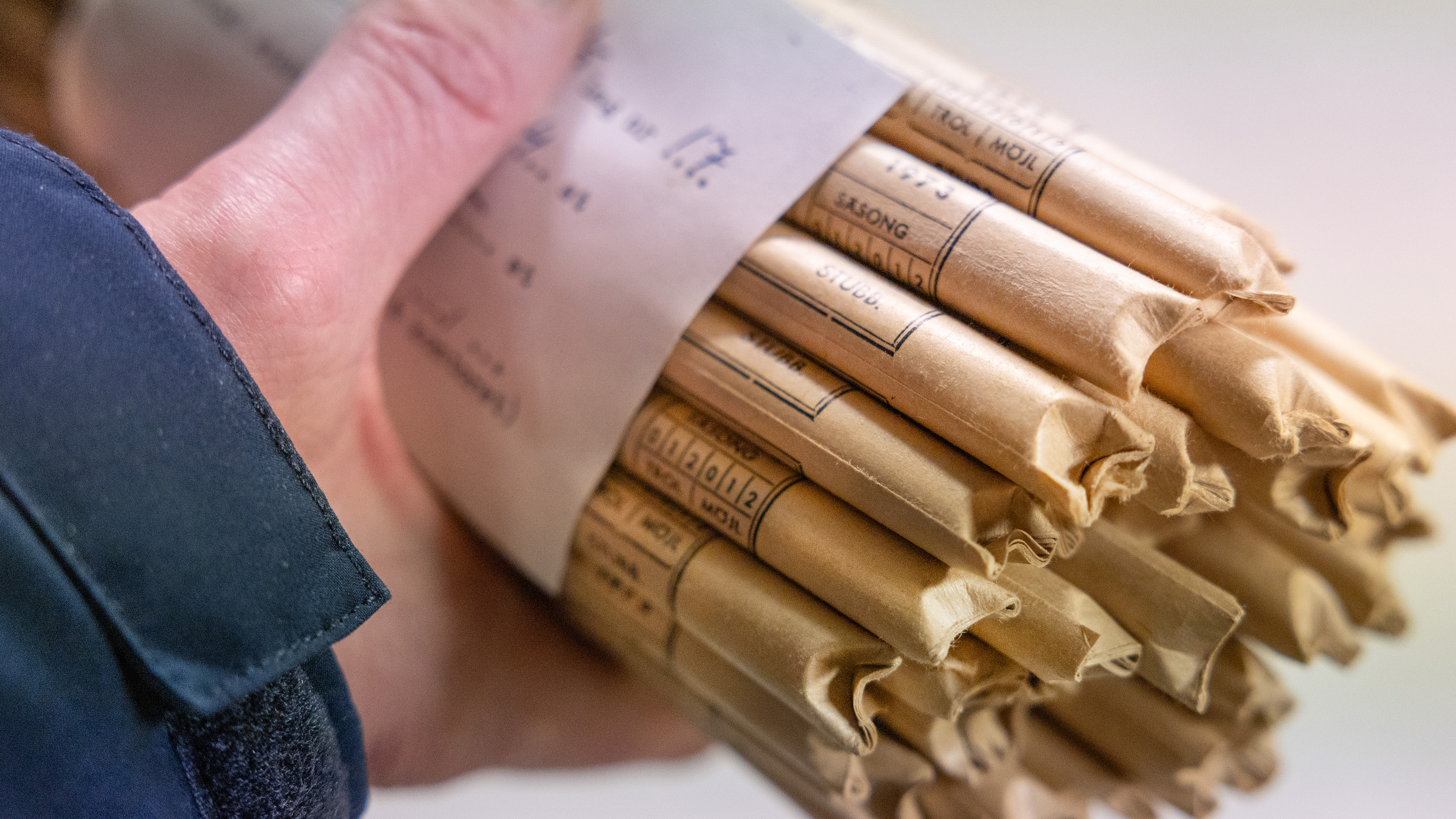 Hand som håller en bunt med smala pappersfickor.