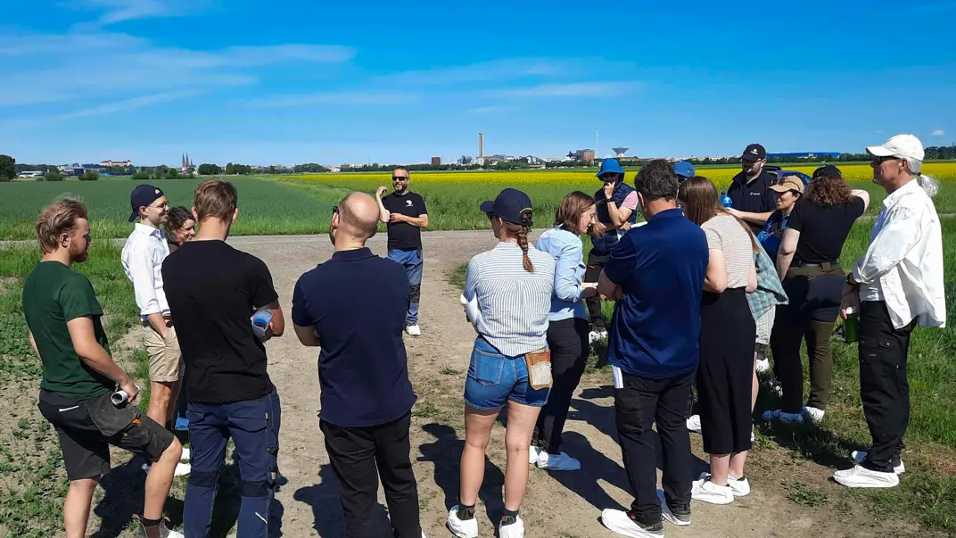 Many people are standing on a field under a blue sky. Photo.