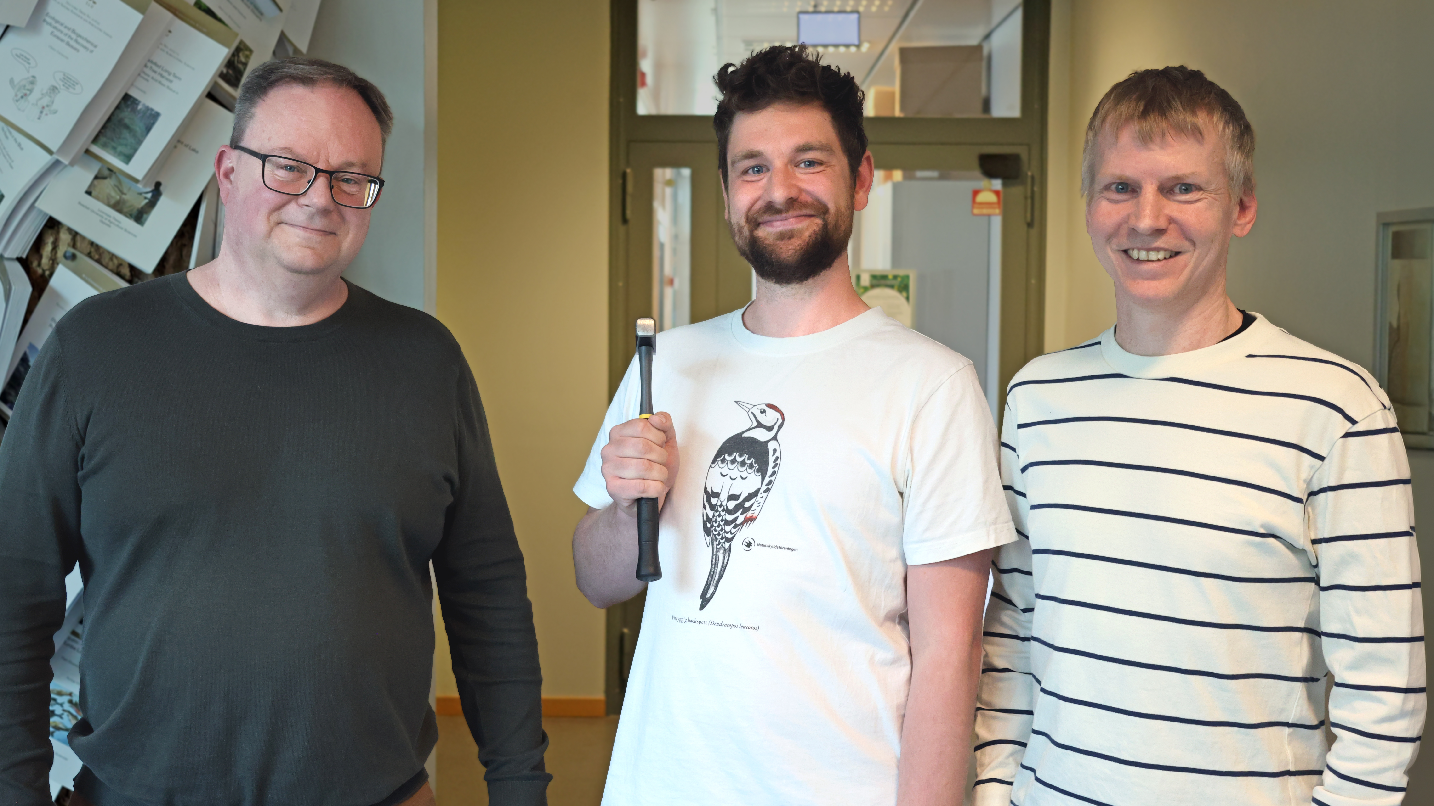 Tre killar, den mittersta håller en hammare. Foto.