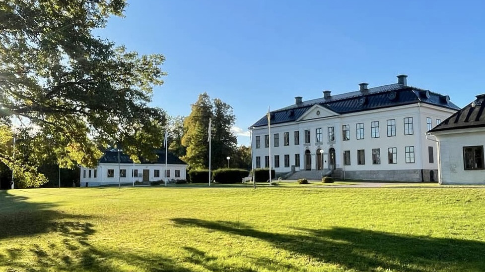 White building by a lawn and trees.