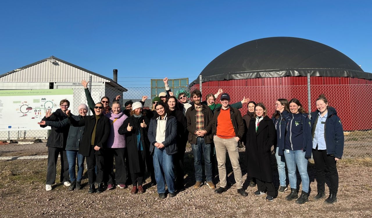 Glada studenter framför en biogasanläggning