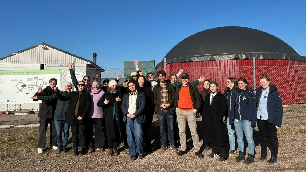 Glada studenter framför en biogasanläggning
