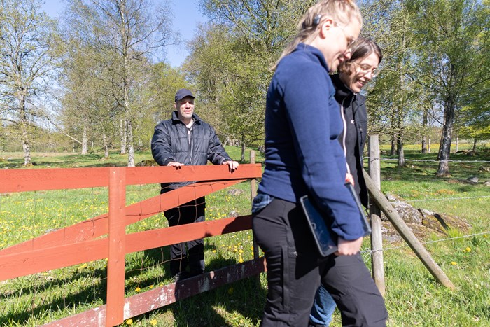 En skogsägare och två forskare vid en grind