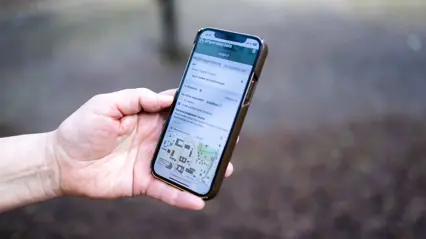 A hand holds a phone showing Artportalen. Photo