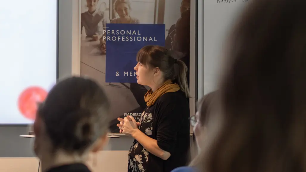 Ung kvinna håller föredrag i mötesrum. Foto