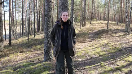kvinna står lutat mot träd
