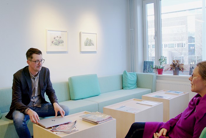 Erik Hysing sitting by a table discussing something with a colleague.
