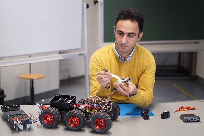 Abozar Nasirahmadi sitting by a table making adjustments to digital equipment.