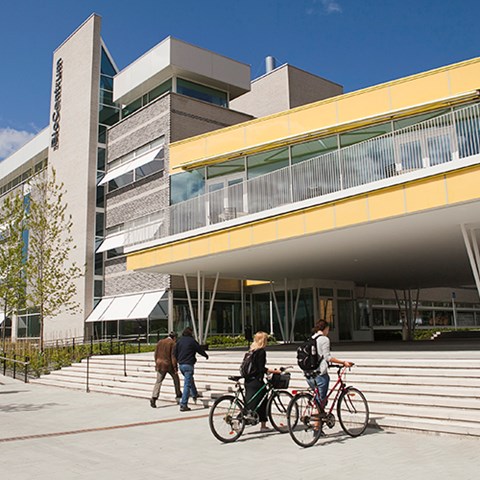 Two students lead their bicycles outside Biocentrum at Ultuna. Photo.