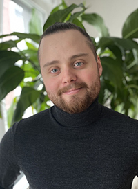 Portrait photo of a man in front of a green plant indoors. Photo. 