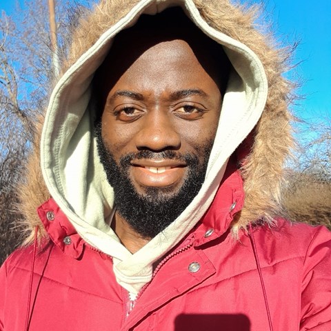 An image of a man smiling at the camera. He is wearing a winter jacket.