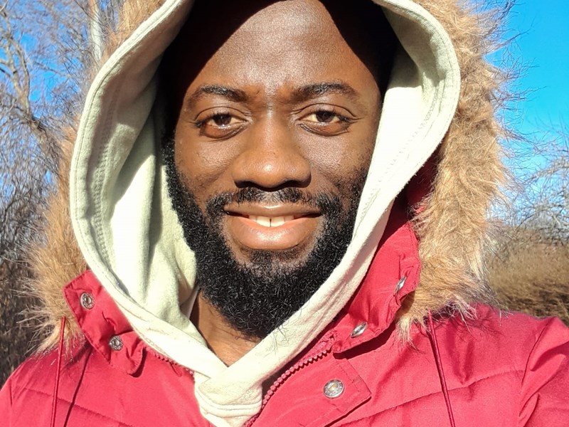 An image of a man smiling at the camera. He is wearing a winter jacket.