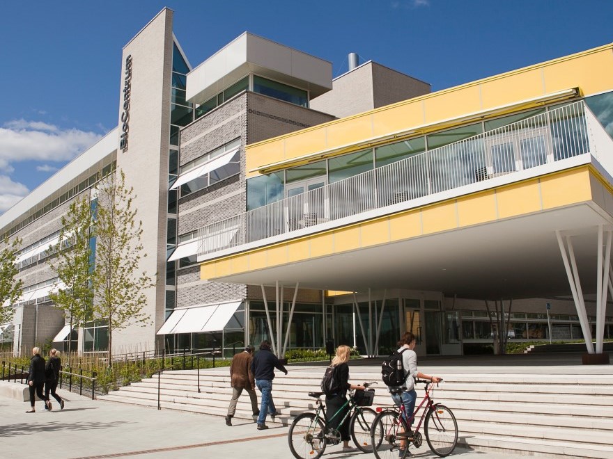 Students walk with their bikes across campus, photo.