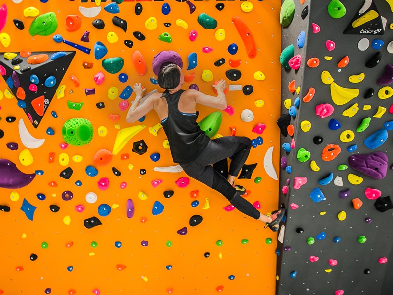 Kvinna klättrar på en färgglad klättervägg, foto.