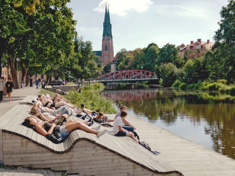 Några människor vilar vid ån i centrala Uppsala. foto
