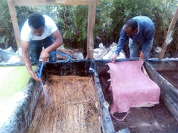 Two people at a compost outdoors, photo.