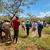 People in a dry grass landscape standing and talking/listening to each other