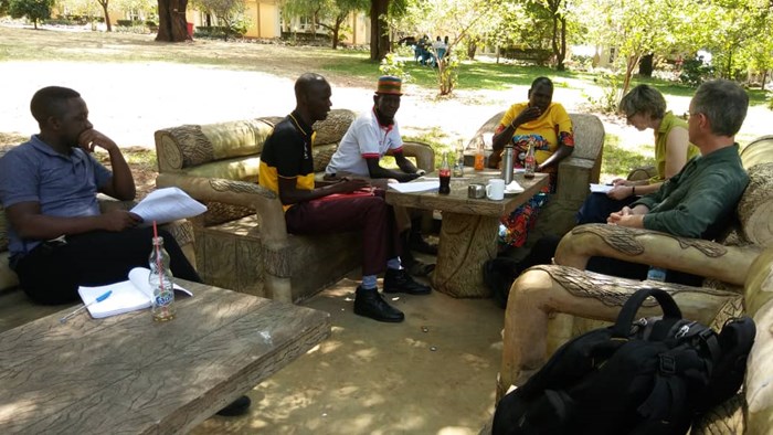 Six persons are discussing under a tree in Uganda
