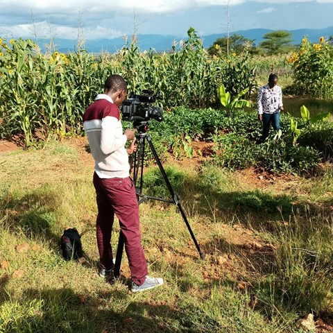 An african man is filming another man in a farm