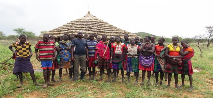 Women and men in front of traditional house in Eastern Uganda