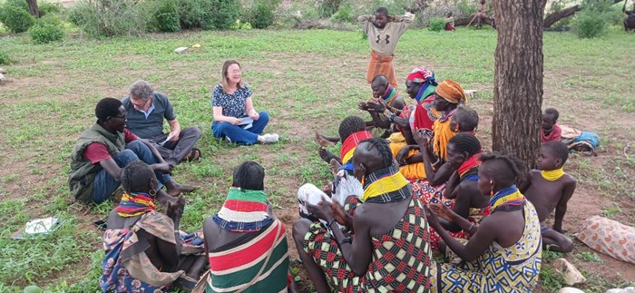 Women sit in a circle under a tree