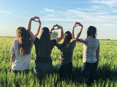 Fyra flickor håller varandra i hand på ett fält