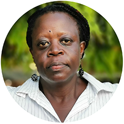 A head picture of a woman with dark skin and black hair, wearing a white blouse. Photo.