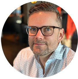 Headshotof a man with short dark hair wearing glasses. Photo.