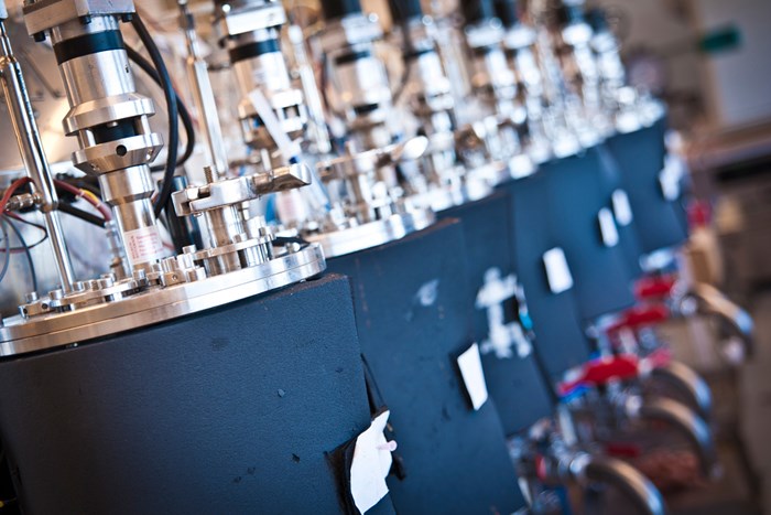 Blue, cylindrical machines in a row indoors, photo.