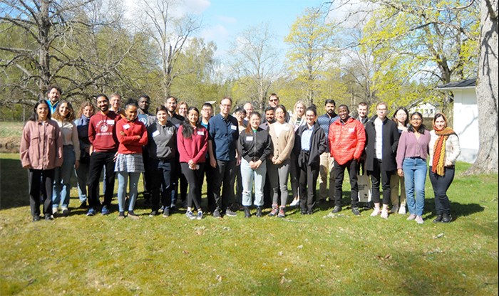 Ungefär 30 personer står uppställda i en rad utomhus. Foto.