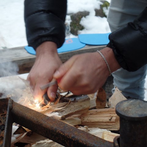 Close up on hands making fire at an outdoor fire place. Photo,