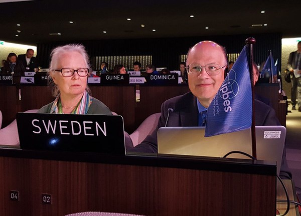 Två personer i den svenska delegationen sitter vid ett förhandlingsbord vid ett möte. Foto.