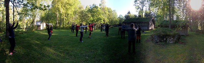 Ett tiotal personer som utför qigong utomhus. Foto.