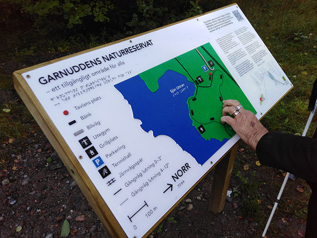 Person läser taktil karta över Garnuddens naturreservat.